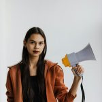 Confident woman in casual attire holding a megaphone, symbolizing activism and protest.